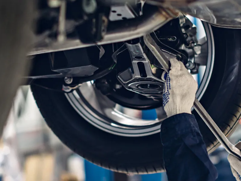 整備士が車の足回りを点検し異常振動を確認する様子